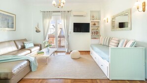 A modern living room with a sofa, a coffee table, and a television. - Bright, Calming Retreat With Balcony Near Metro! (Menemeni)