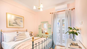 A bedroom with a bed, bedside table, dresser, and a window with curtains. - Bright, Calming Retreat With Balcony Near Metro! (Menemeni)