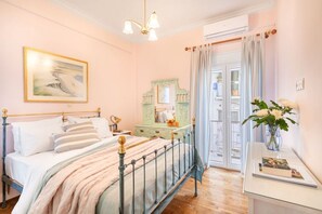 Ein Schlafzimmer mit Bett, Nachttisch, Kommode und einem Fenster mit Vorhängen.