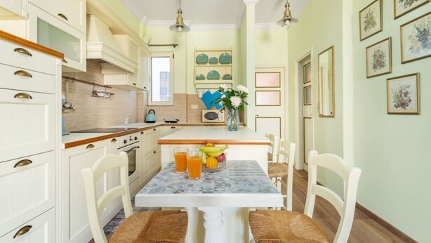 A kitchen with white cabinets, a marble table, and wicker chairs. - Bright, Calming Retreat With Balcony Near Metro! (Menemeni)
