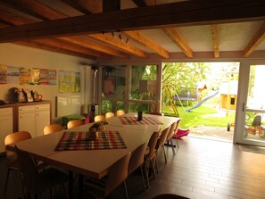 A dining area with a table, chairs, and a view of a playground through large windows. - Apartment 1 with Terrace, Garden and Wi-Fi (Überlingen)