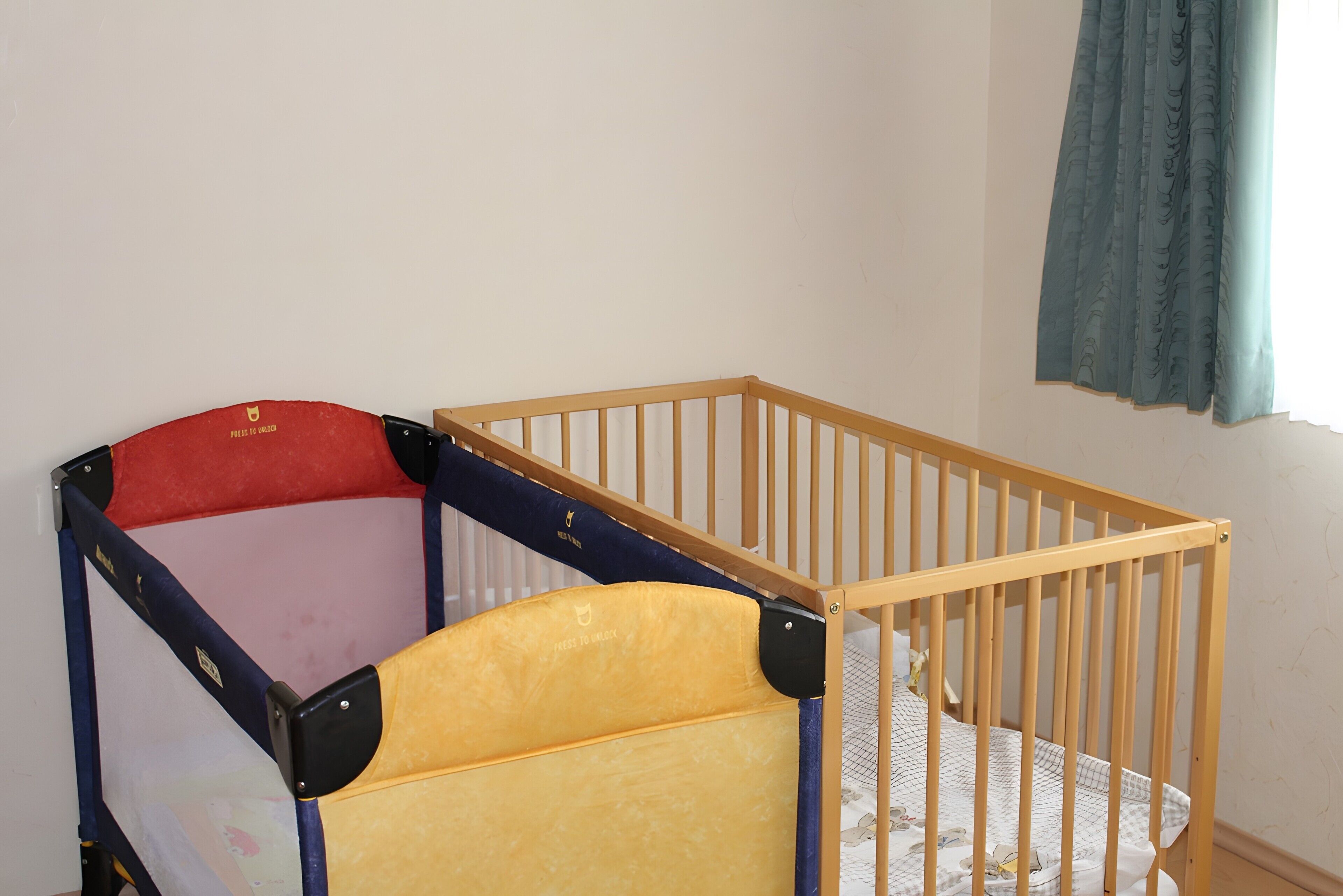 Ein Zimmer mit einem hölzernen Kinderbett und einem Beistellbettchen.