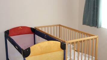 Ein Zimmer mit einem hölzernen Kinderbett und einem Beistellbettchen.