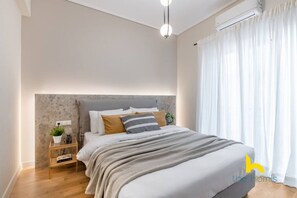 A modern bedroom with a bed, bedside table, and a nightstand. - Minimal 2-BDR Apt Near Acropolis By The Homis (Athina)