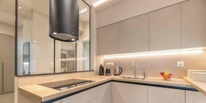A modern kitchen with a built-in stove, a sink, and a fruit bowl on the counter. - Minimal 2-BDR Apt Near Acropolis By The Homis (Athina)