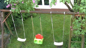 A wooden swing set with two swings, one green and one white, suspended by ropes. - Apartment '2' with Balcony, Garden and Wi-Fi (Überlingen)