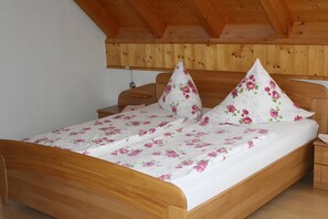 A wooden bed with a floral bedspread and two pillows.