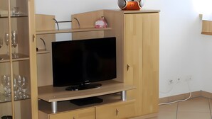 A TV on a wooden cabinet with a shelf above it and a drawer below. - Apartment '3' with Balcony, Garden and Wi-Fi (Überlingen)