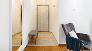 A hallway with a bench, a door, and a chair with a blanket. - Head for Acropolis from a Romantic Nest in Koukaki (Athina)