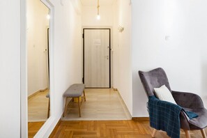 A hallway with a bench, a door, and a chair with a blanket. - Head for Acropolis from a Romantic Nest in Koukaki (Athina)
