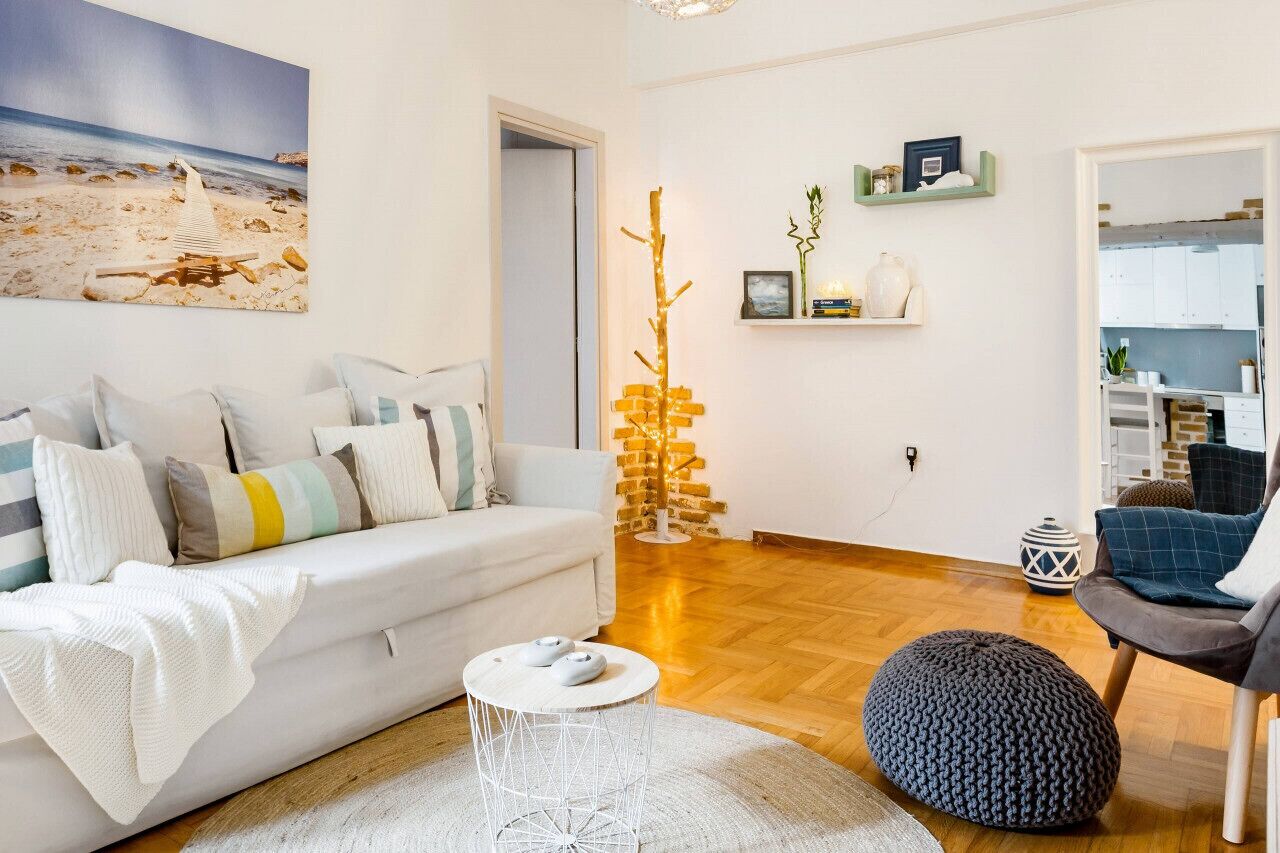 A modern living room with a white sofa, a round coffee table, and a wooden floor.