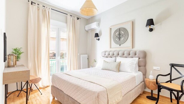 Een slaapkamer met een bed, bureau, stoel, hanglamp en een raam met gordijnen.