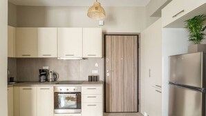 Een moderne keuken met lichte kastjes, een ingebouwde oven, een roestvrijstalen koelkast en een houten deur.