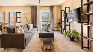 A modern living room with a sofa, coffee table, and TV. There is a balcony with a view of buildings. - Acropolis View, Minimal-Safari Vibe, Big Balcony! (Athina)