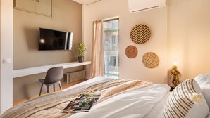 A hotel room with a bed, a desk with a chair, a television, and a window with curtains. - Acropolis View, Minimal-Safari Vibe, Big Balcony! (Athina)