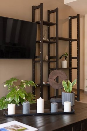 Uma prateleira de madeira escura com plantas em vasos e velas.