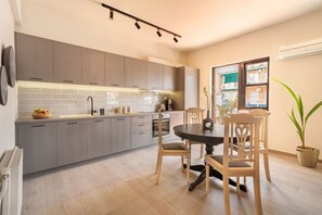 A modern kitchen with grey cabinets, a round dining table with wooden chairs, and a potted plant. - Acropolis View, Minimal-Safari Vibe, Big Balcony! (Athina)