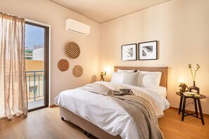 A bedroom with a bed, a window with curtains, a wall-mounted air conditioner, and two framed pictures. - Acropolis View, Minimal-Safari Vibe, Big Balcony! (Athina)