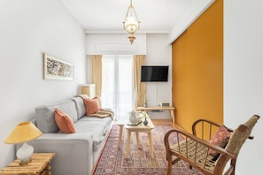 Un salon moderne comprenant un canapé, un fauteuil, une table basse et un téléviseur.