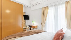 A hotel room with a bed, a desk with a lamp, a TV, and curtains. - Chill Out In Retropolitan Hideaway at Alsos Park (Athina)