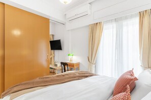 A hotel room with a bed, a desk with a lamp, a TV, and curtains. - Chill Out In Retropolitan Hideaway at Alsos Park (Athina)