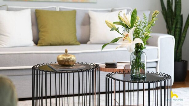 A modern living room with a white sofa, green and white cushions, a glass coffee table with a decorative item, and a vase with flowers. - Contemporary 2-BDR APT near Kalimarmaro & Alsos! (Athina)