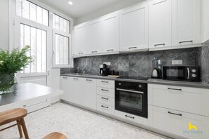 A modern kitchen with white cabinets, a black oven, a microwave, and a marble countertop. - Contemporary 2-BDR APT near Kalimarmaro & Alsos! (Athina)