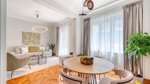 A modern living room with a round dining table, a sofa, and a large window with curtains. - Contemporary 2-BDR APT near Kalimarmaro & Alsos! (Athina)