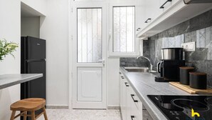 A modern kitchen with a black refrigerator, a coffee maker, and a stove. - Contemporary 2-BDR APT near Kalimarmaro & Alsos! (Athina)