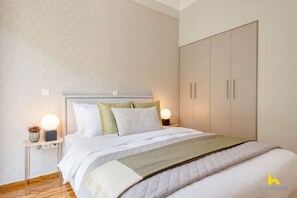 Une chambre à coucher comprenant un lit, des tables de chevet, une armoire et un mur orné d’un motif discret.