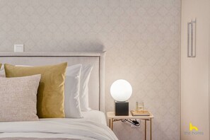 A neatly made bed with a headboard, a bedside table with a lamp, and a wall-mounted light fixture. - Contemporary 2-BDR APT near Kalimarmaro & Alsos! (Athina)
