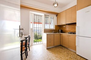 Eine Küche mit Holzausstattung, einem weißen Kühlschrank, einem Esstisch mit Stühlen und einem Fenster mit Metallgitter.