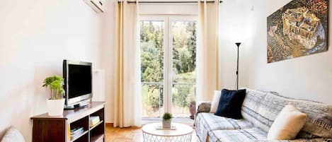 Un salon avec un canapé, un téléviseur, une table basse et un tableau accroché au mur.