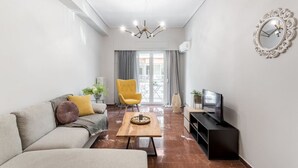 A modern living room with a sofa, a yellow armchair, a coffee table, a TV, and a decorative mirror. - Explore History from a Chic Central Apartment (Athina)