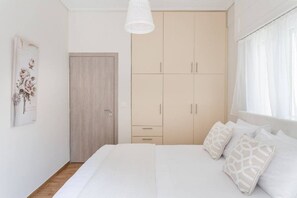 A bedroom with a bed, a wardrobe, and a door. - Explore History from a Chic Central Apartment (Athina)