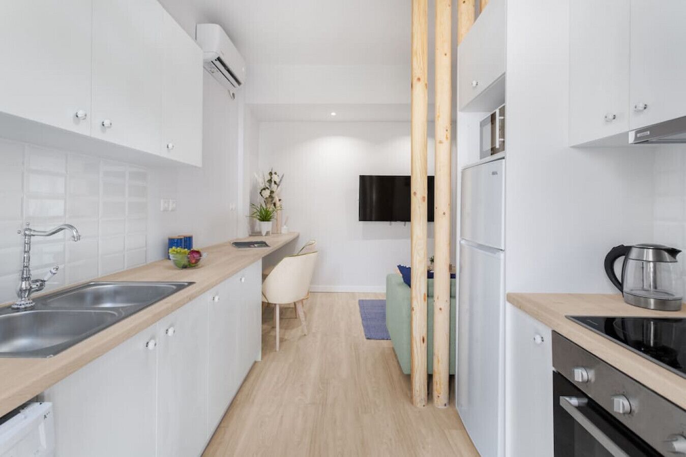 Una cocina moderna con armarios blancos, electrodomésticos de acero inoxidable y encimera de madera.