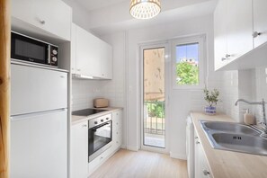 A compact kitchen with white cabinetry, a built-in oven, a microwave, and a toaster. - Modern & Stylish Hideaway Downtown near Acropolis (Athina)