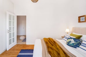 A bedroom with a bed, a nightstand, a lamp, a wall-mounted picture, and a door leading to another room. - Modern & Stylish Hideaway Downtown near Acropolis (Athina)