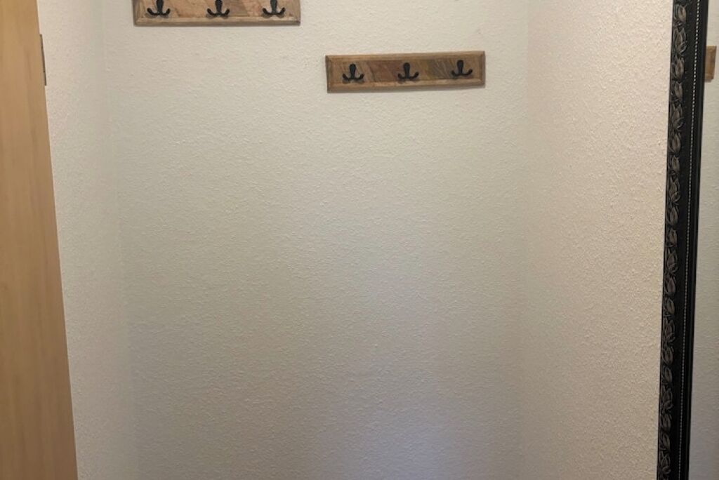 Un mur blanc sur lequel sont fixées deux plaques en bois portant des noms.