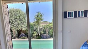 Ein Schlafzimmer mit Bett, Blick auf einen Pool und einer Tür, die nach draußen führt.