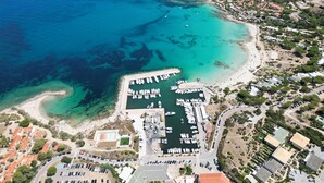 Luftaufnahme einer Küstenregion mit einem Yachthafen, Strand und Wohnhäusern.