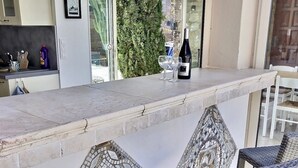 Eine moderne Küche mit Bar, Korbstühlen und Blick auf Grünflächen.