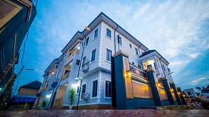A multi-story building with a prominent entrance, large windows, and a balcony. - Evanluck Luxury Homes (Lagos)