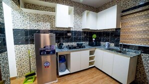 A kitchen with white cabinets, a stainless steel refrigerator, a coffee maker, and a blender. - Evanluck Luxury Homes (Lagos)
