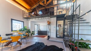 Ein modernes Interieur mit Essbereich, einem schwarzen Fellteppich und einer Treppe zu einer oberen Ebene.