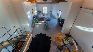Ein geräumiger Wohnbereich mit hoher Decke, einer Treppe und einem Essbereich mit Glastisch.