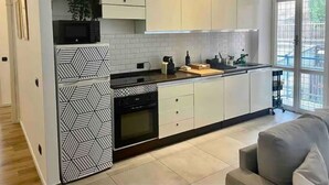 Een moderne keuken met witte kasten, een zwart-wit betegelde achterwand en een klok aan de muur.