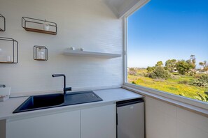 Een koelkast, een waterkoker, kookgerei, borden en bestek