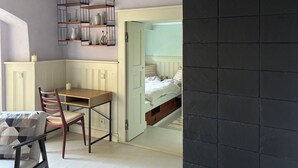 Quarto com mesa de jantar, cadeiras, um banco fixo, uma estante com objetos decorativos e uma cama com cabeceira.