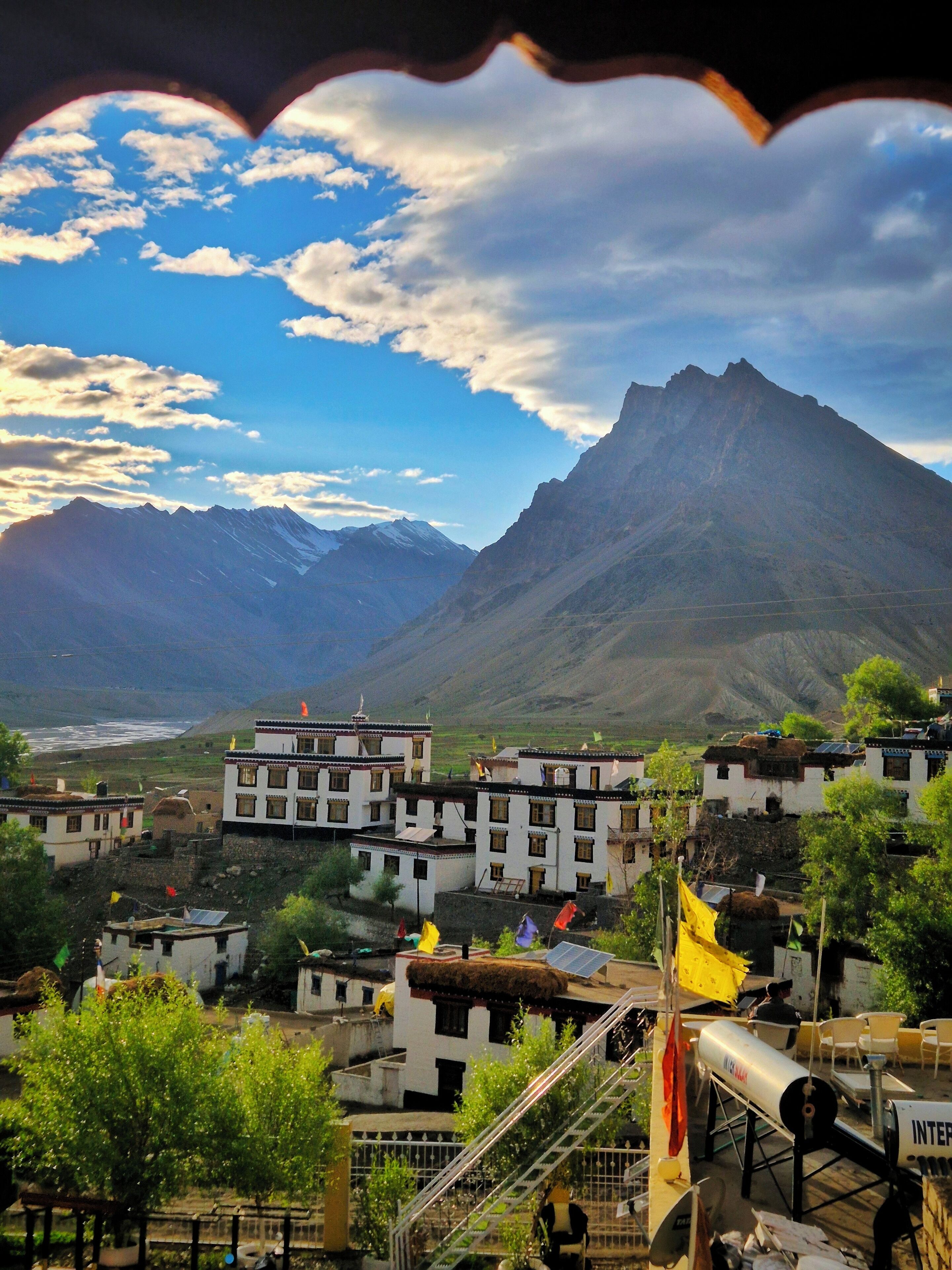A mountainous landscape with traditional buildings, a clear sky, and a prominent peak.